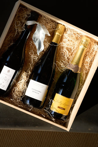 Three bottles of wine in a wooden gift box with straw lining.