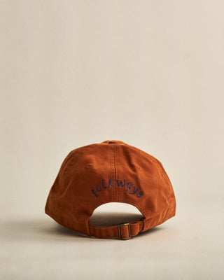 Brown cap with folkways on the back against a beige background