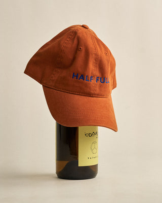 Orange cap with 'HALF FULL' text on a bottle of wine against a beige background