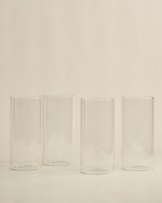 Four clear glass tumblers on a beige background
